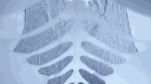 a person is cutting a piece of fabric into the shape of a skeleton on a white surface .