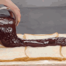 a person is pouring chocolate sauce onto slices of bread