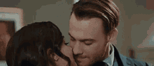 a man and a woman are kissing in a room .