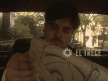 a man is reading a newspaper with el trece written on the bottom right