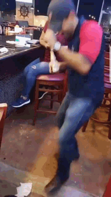 a man is dancing in a restaurant while a woman sits at a bar