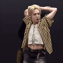 a man wearing a striped shirt and a crop top is dancing .