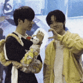 two young men are standing next to each other and one has a stuffed animal on his arm