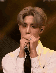 a young man in a white shirt and tie is holding a microphone in his hands .