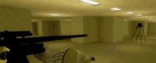 a person is holding a sniper rifle in a room with a tripod .