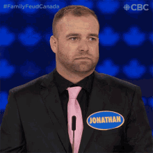 a man in a black suit and pink tie has a name tag that says jonathan
