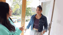 two women are standing in front of a door talking to each other