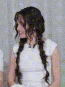 a woman in a white dress is sitting on a couch with her hair in braids .