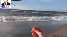 a person standing on a beach with a picture of a man and the words true