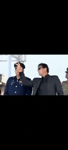 two men in military uniforms are standing next to each other and talking to each other .