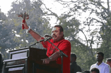 a man in a red shirt is speaking into a microphone while holding a red object