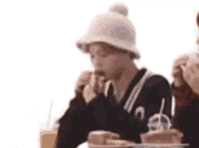 a person wearing a hat is sitting at a table with a plate of food .