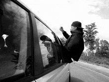a black and white photo of a man sticking his head out of a car