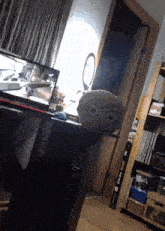 a smiley face pillow sits on a desk in front of a computer