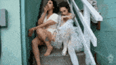 two women are sitting on a set of stairs smoking cigarettes