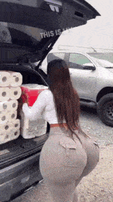 a woman is loading toilet paper into the back of a truck