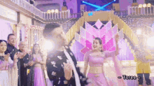 a man and a woman are dancing in front of a crowd with the word toree above them