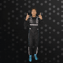 a man in a petronas suit is dancing in front of a black background