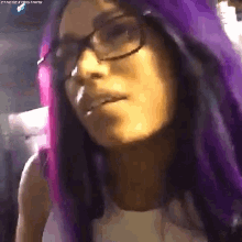 a woman with purple hair and glasses is making a face .