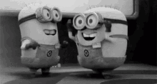 two minions are standing next to each other and dancing in a black and white photo .