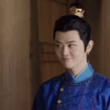 a man in a blue robe and a crown on his head is smiling .