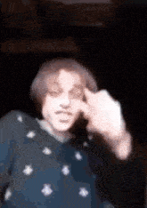 a blurry picture of a man making a funny face with his hand on his forehead .