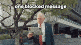 a man in a suit and tie is reading a newspaper with the words one blocked message above him