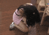 a woman in a pink dress is kneeling on the floor with her head down