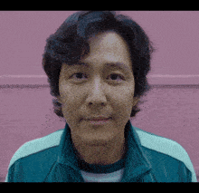 a close up of a man 's face with a pink wall behind him