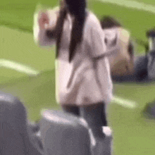 a woman is standing on top of a soccer field holding a bottle of water .