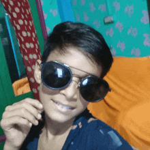 a young boy wearing sunglasses takes a picture of himself