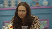 a woman wearing a leopard print jacket is sitting at a table with a glass of water .