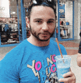 a man wearing a blue shirt that says young bug is drinking from a cup with a straw