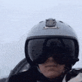 a person wearing a helmet and goggles is standing in front of a cloudy sky .