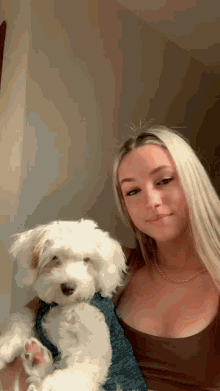 a woman is holding a small white dog in her arms while posing for a picture .