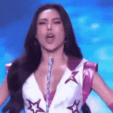 a woman with long hair is singing into a microphone while wearing a very revealing outfit with stars on it .