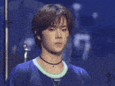 a young man wearing a choker necklace and ear buds has a tattoo on his face