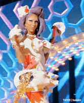 a drag queen is dancing on a stage with a flamingo in her hand ..