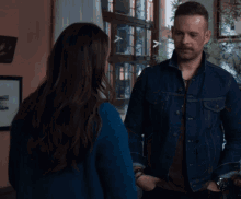 a woman in a blue jacket is hugging a man