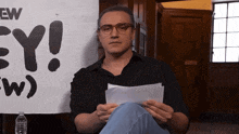 a man is sitting in front of a sign that says ew