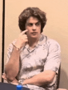 a young man is sitting at a table making a funny face .