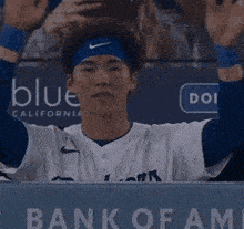 a baseball player sitting in the dugout with a bank of fame sign in the background