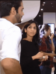 a man in a white shirt is standing next to a woman in a black dress