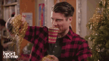 a man in a plaid shirt is drinking from a cup with the words heart and home on it