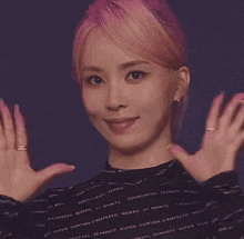 a woman with pink hair is wearing a black sweater with the word aspen on it