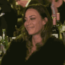 a woman sitting at a table with bottles of wine on it