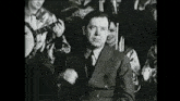 a man in a suit is standing in front of a group of people playing instruments .