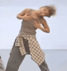 a woman in a plaid shirt is dancing on a beach