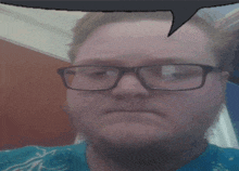 a man wearing glasses and a blue shirt has a speech bubble over his head .