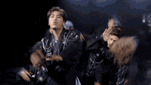 a group of young men are dancing in a dark room and one of them is wearing a black jacket with a korean symbol on it